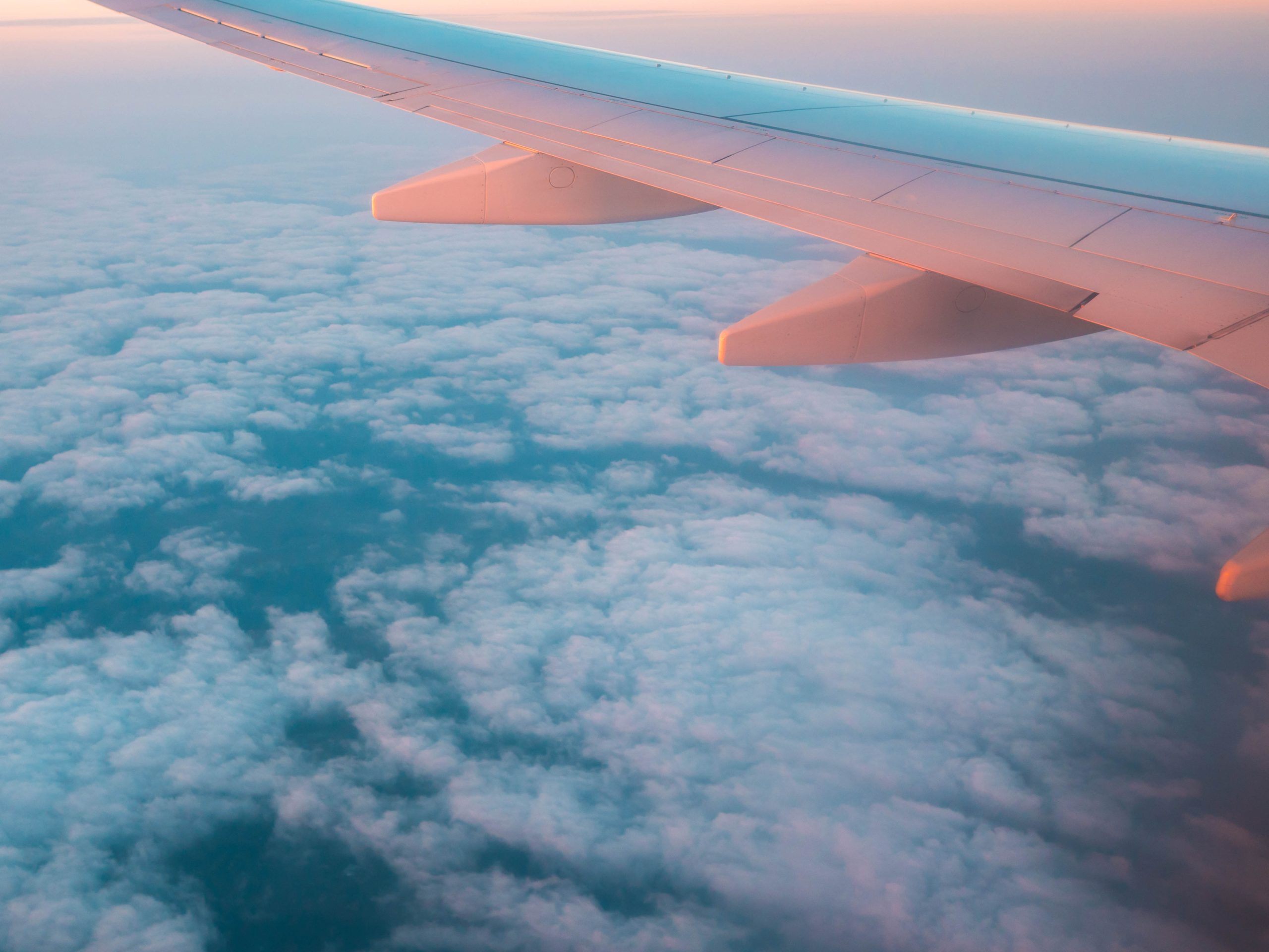 Asa de avião sobre nuvens no pôr do sol